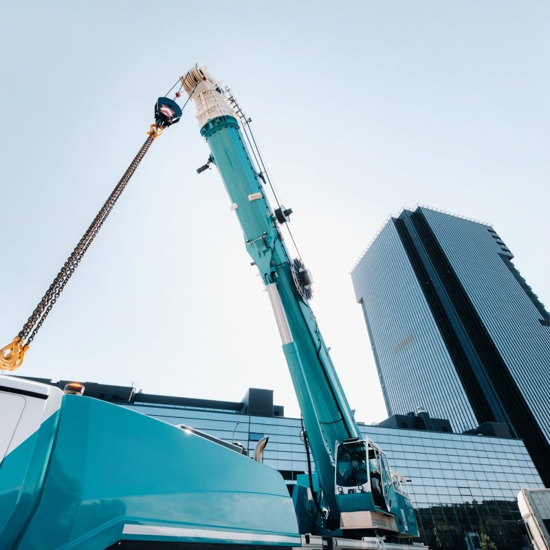 blue crane lifting mechanism with hooks near the glass modern building, crane and hydraulic high